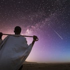 Ethiopia. Rear view of a senior ethiopian man carrying his stick over his shoulder and watching the milky way in a starry sky.